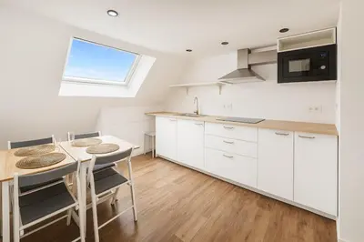 a kitchen with white cabinets and a table and chairs at Modern Loft 1BR Sofa Bed 10min to Center in Brussels