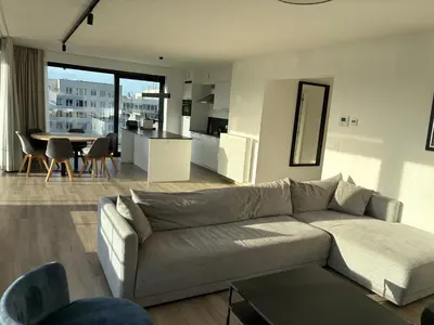 a living room with a couch and a kitchen and a table at Penthouse avec vue imprenable sur Bruxelles in Brussels