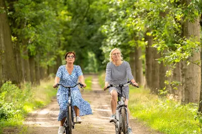 two women riding bikes down a dirt road at 15 inn in Mol