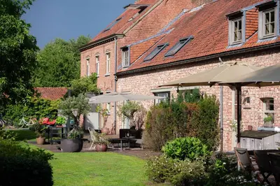 a brick building with tables and umbrellas in a yard at 15 inn in Mol