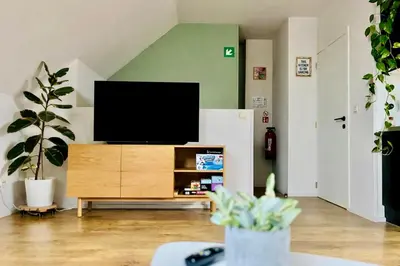a living room with a flat screen tv on a wooden cabinet at Ruime studio met eigen ingang en private badkamer in Opwijk