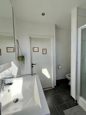 a white bathroom with a sink and a toilet at Ruime studio met eigen ingang en private badkamer in Opwijk