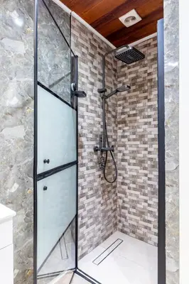 a shower with a glass door and a brick wall at Apartment-Gravensteen in Ghent