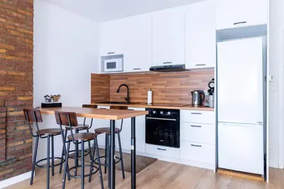 a kitchen with white cabinets and a wooden island with bar stools at Apartment-Gravensteen in Ghent