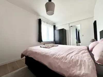 a bedroom with a large bed with a pink comforter at lovely 2room Elegant Apartment in Brussels for 2people in Brussels