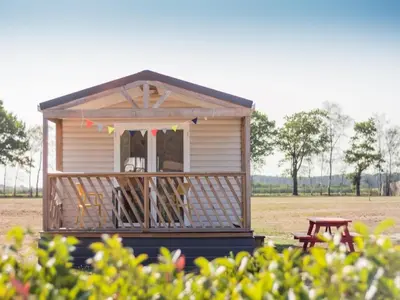 a small house with a bench in a field at Beach lodge with lake view in Ravels in Ravels