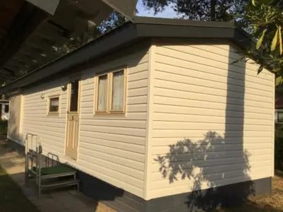 a small white cabin with a window and a door at Stay with Beach and Minigolf Views in Ravels