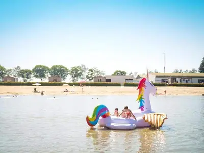 two children are riding on an inflatable unicorn in the water at Cordelia Lodge with Garden & Picnic Area in Ravels