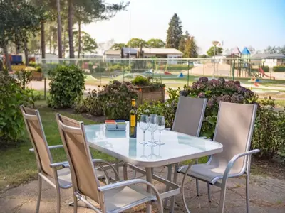 a table and chairs with wine glasses and a playground at Luxury Forest Lodge with Private Garden in Ravels