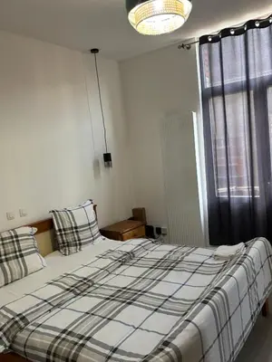 a bedroom with a bed with a checked blanket and a window at Suzanne house in Brussels
