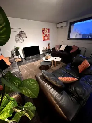a living room with a leather couch and a flat screen tv at Maison Melis Antwerp in Antwerp