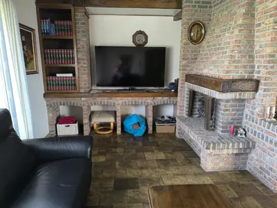 a living room with a brick fireplace with a flat screen tv at Willa Sunny Garden in Sint-Laureins