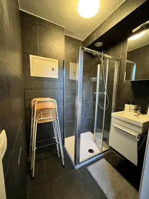 a bathroom with a shower and a stool next to a sink at sint-pietersplein duplex 9 in Ghent