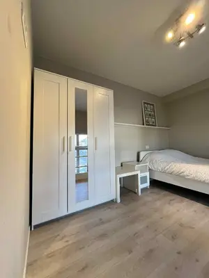 a bedroom with a bed and a white cabinet at sint-pietersplein duplex 9 in Ghent