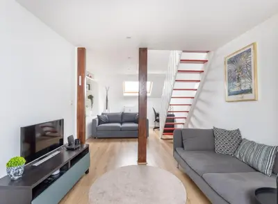 a living room with a couch and a staircase at Escapade cosy Quartier EU Place Jourdan in Brussels
