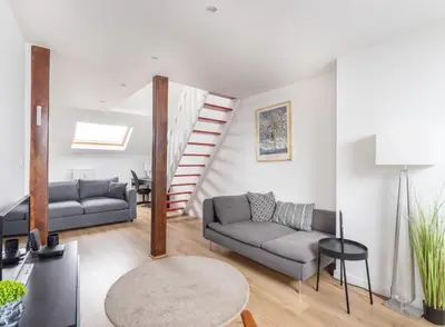 a living room with two couches and a staircase at Escapade cosy Quartier EU Place Jourdan in Brussels