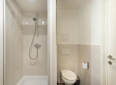 a white bathroom with a shower and a toilet at Escapade cosy Quartier EU Place Jourdan in Brussels