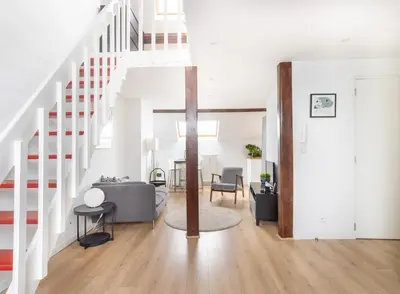 a living room with white walls and a staircase at Escapade cosy Quartier EU Place Jourdan in Brussels