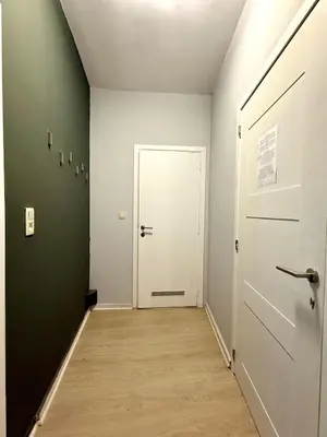 a hallway with a white door and a wooden floor at 3 min to the Grand-Place 6 min to Manneken Pis & Sleeps 6 in Brussels