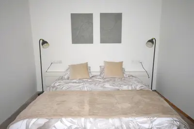 a bed in a white room with two lamps at De Durme in Temse