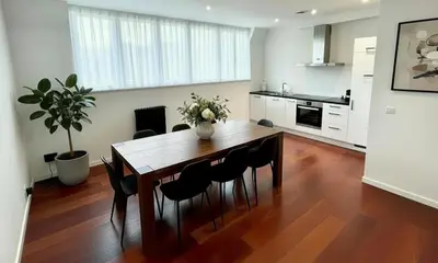 a kitchen with a wooden table with chairs and a vase of flowers at Rooms at Université Libre de Bruxelles in Brussels