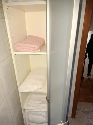 a closet with white shelves with towels in it at Chambres dans un Immeuble in Brussels