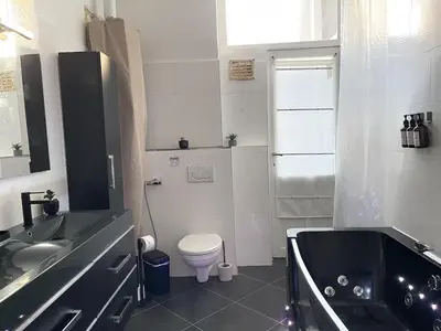 a bathroom with a tub and a toilet and a sink at Beautiful condominium with jacuzzi in Brussels