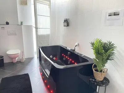 a bathroom with a black tub with red lights at Beautiful condominium with jacuzzi in Brussels