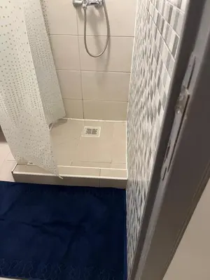 a shower with a shower curtain and a blue rug at Studio confortable situé à Woluwe Saint Lambert in Brussels