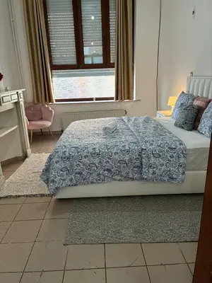 a bedroom with a bed with a blue comforter and a window at Chambres et appartement dans un immeuble in Brussels