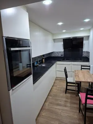 a kitchen with white cabinets and a table with chairs at Chambres et appartement dans un immeuble in Brussels