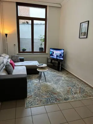 a living room with a couch and a tv at Chambres et appartement dans un immeuble in Brussels