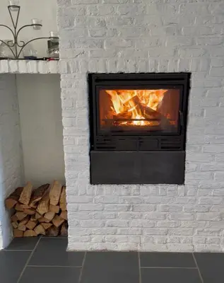 a white brick fireplace with a fire in it at Antwerp West Side, Fireplace in Zwijndrecht