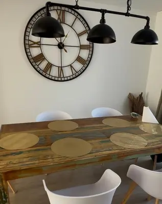 a dining room table with a large clock on the wall at Antwerp West Side, Fireplace in Zwijndrecht