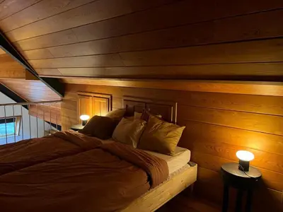 a bed in a room with wooden walls and ceilings at Vakantiewoning - Camping Groenpark in Berlare
