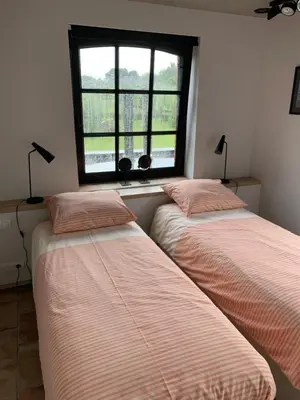 two beds in a room with a window at Vakantiewoning HET HUIS NUMMER 11 in Oosterzele