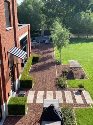 a garden with a table and benches and a building at Vakantiewoning HET HUIS NUMMER 11 in Oosterzele