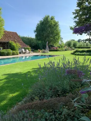 a yard with a swimming pool and a garden with flowers at Vakantiewoning HET HUIS NUMMER 11 in Oosterzele
