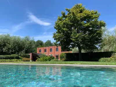 a large swimming pool in front of a brick building at Vakantiewoning HET HUIS NUMMER 11 in Oosterzele
