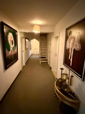 a hallway with a staircase and paintings on the walls at Logies Het Koetshuis in Herentals