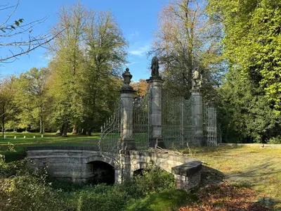 a stone bridge with a fence in a park at Logies Het Koetshuis in Herentals
