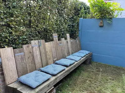 a wooden bench with blue cushions sitting next to a fence at Huisje Scheldevallei in Temse