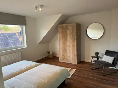 a bedroom with a bed and a mirror and a chair at Huisje Scheldevallei in Temse