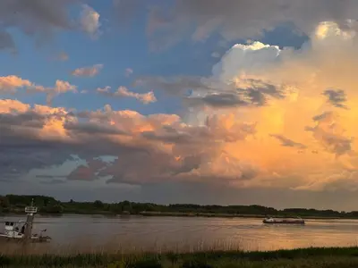 a boat on a river under a cloudy sky at Huisje Scheldevallei in Temse