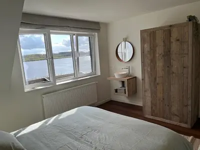a bedroom with a bed and a large window at Huisje Scheldevallei in Temse