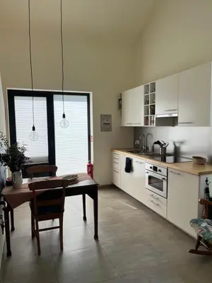 a kitchen with white cabinets and a table in it at Bellefleur Cottage in Herent