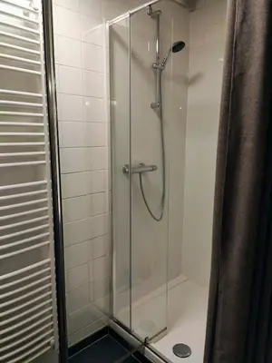 a shower stall with a glass door in a bathroom at Unique Historic Mill Loft with River Lys Views in Ghent