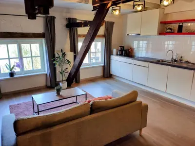 a living room with a couch and a kitchen at Unique Historic Mill Loft with River Lys Views in Ghent