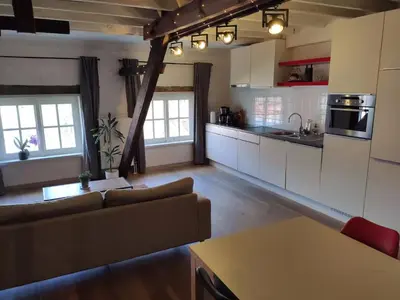 a living room with a couch and a kitchen at Unique Historic Mill Loft with River Lys Views in Ghent