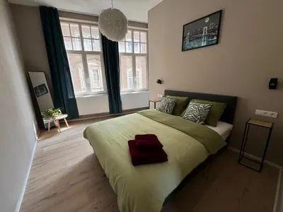 a bedroom with a large bed in a room with windows at Apartment central Lier in Lier